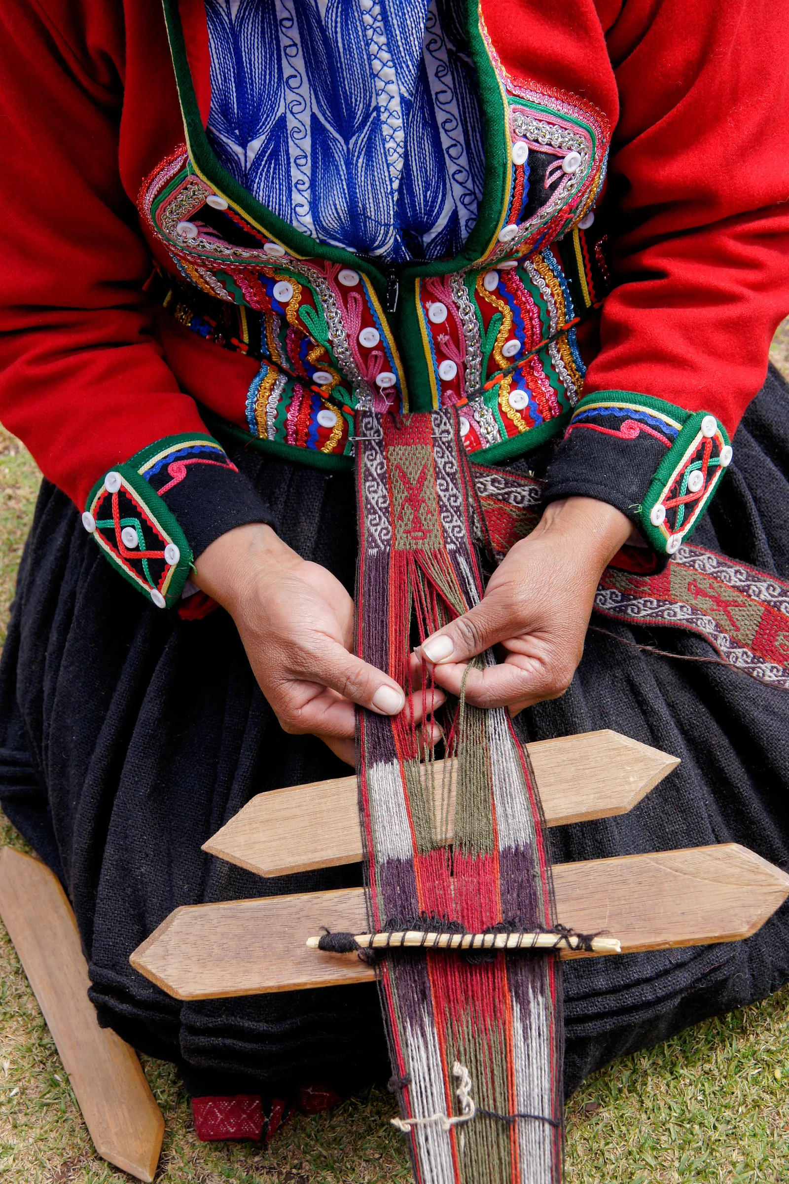 Hands weaving colorful yarn on a wooden loom