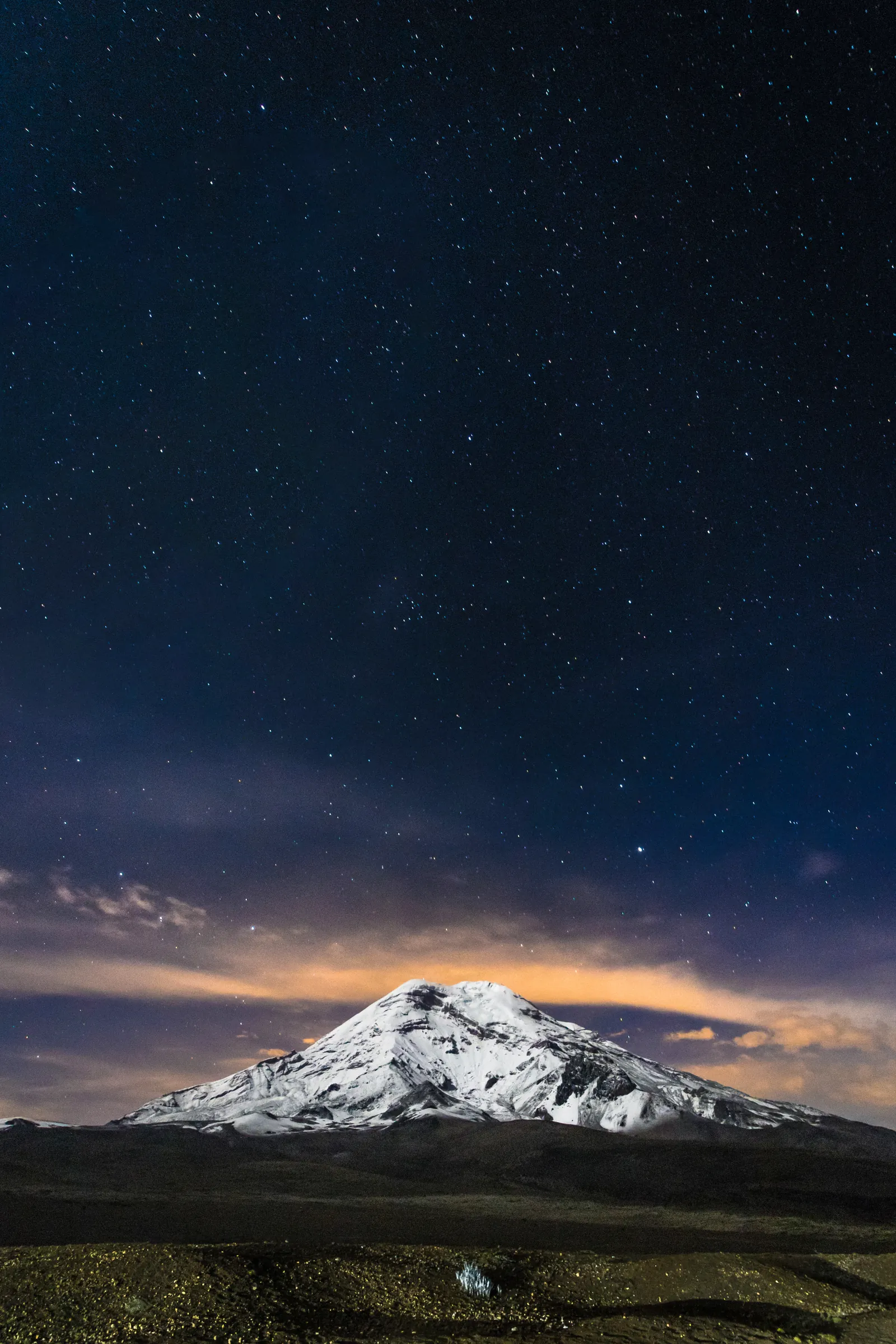 Snowcapped volcano beneath a star-filled night sky