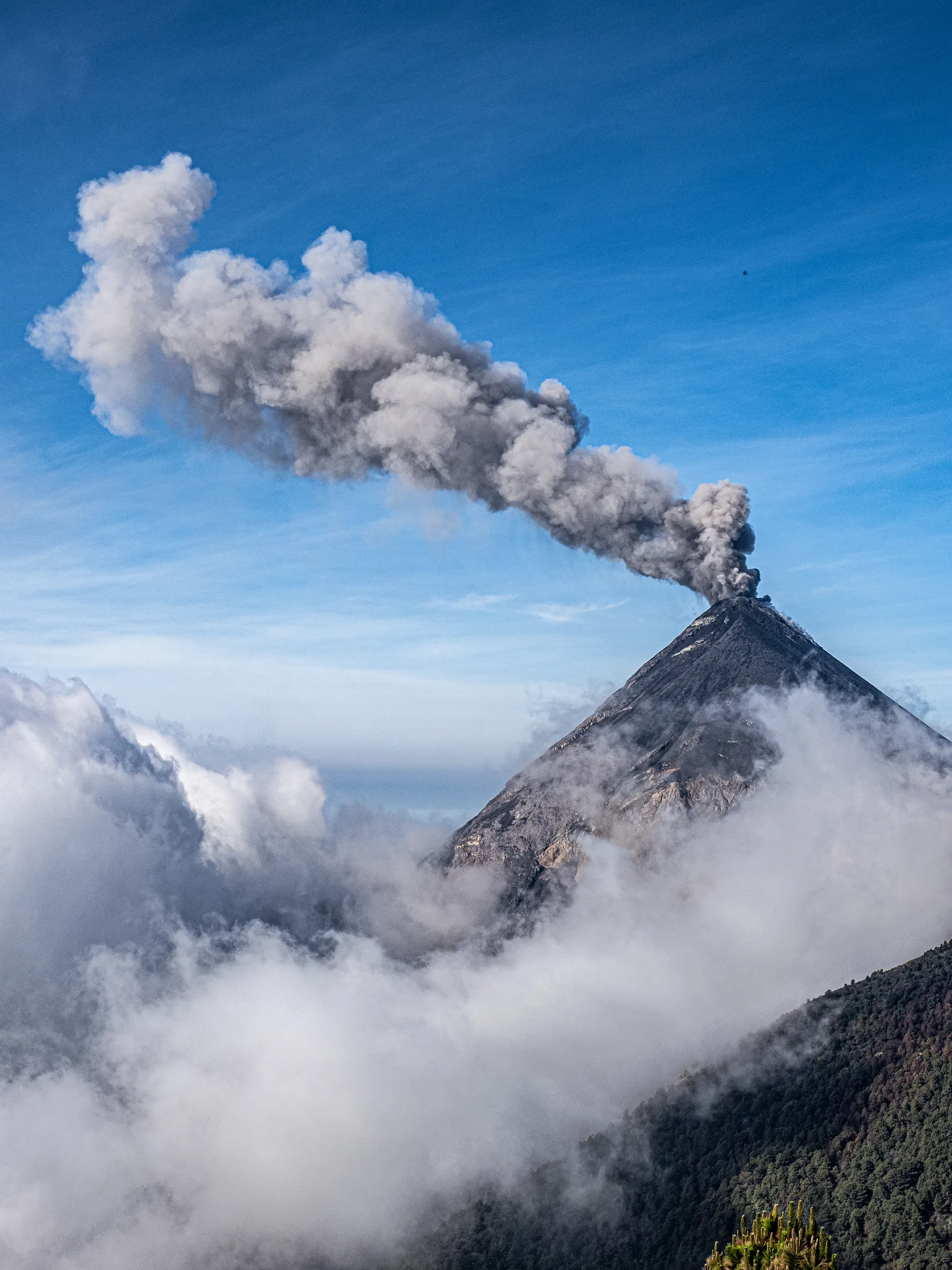 Volcano erupting above clouds
