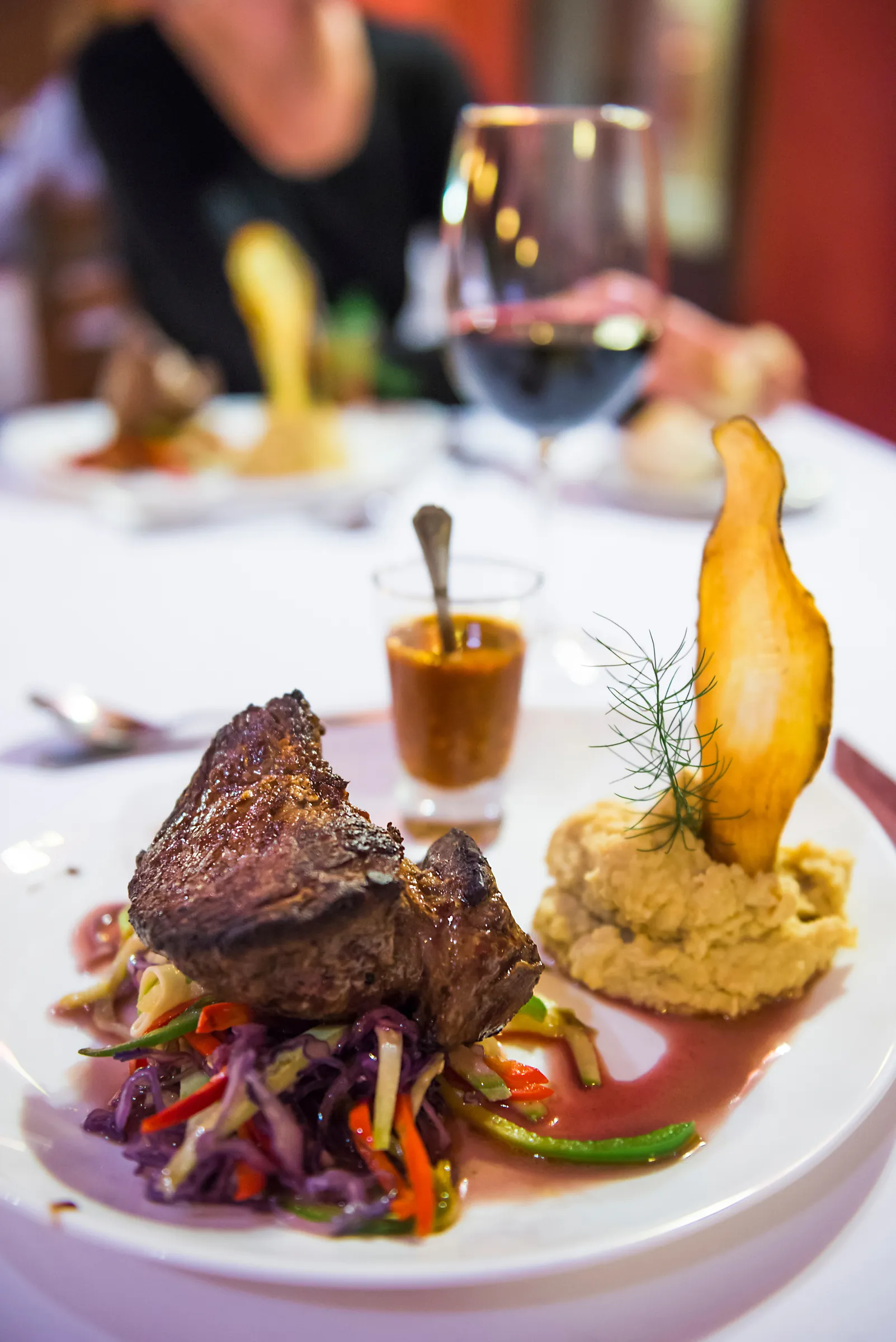 Plated meat dish with vegetables and wine