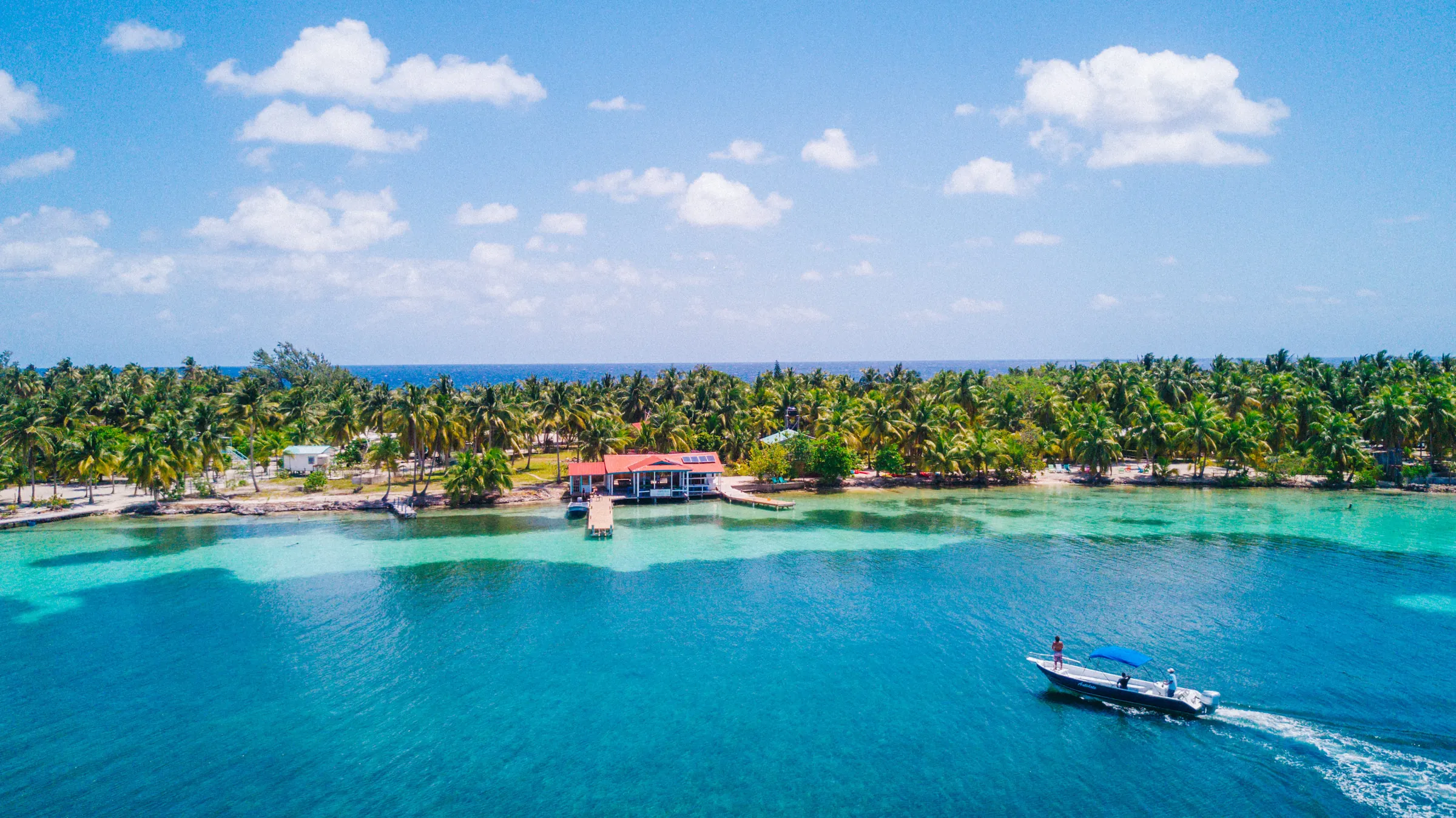 Boat approaching a palm-lined island resort
