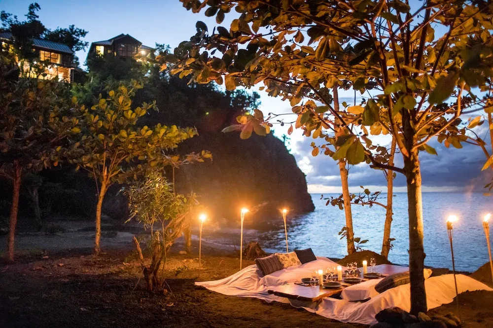 Candlelit seaside seating beneath trees at dusk