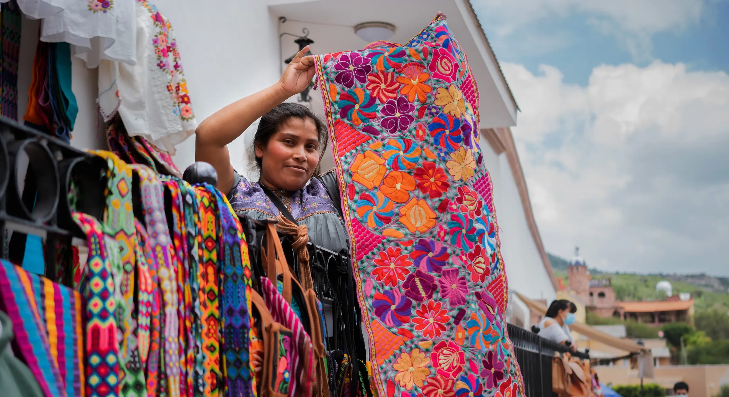 Vendor displaying colorful embroidered textiles