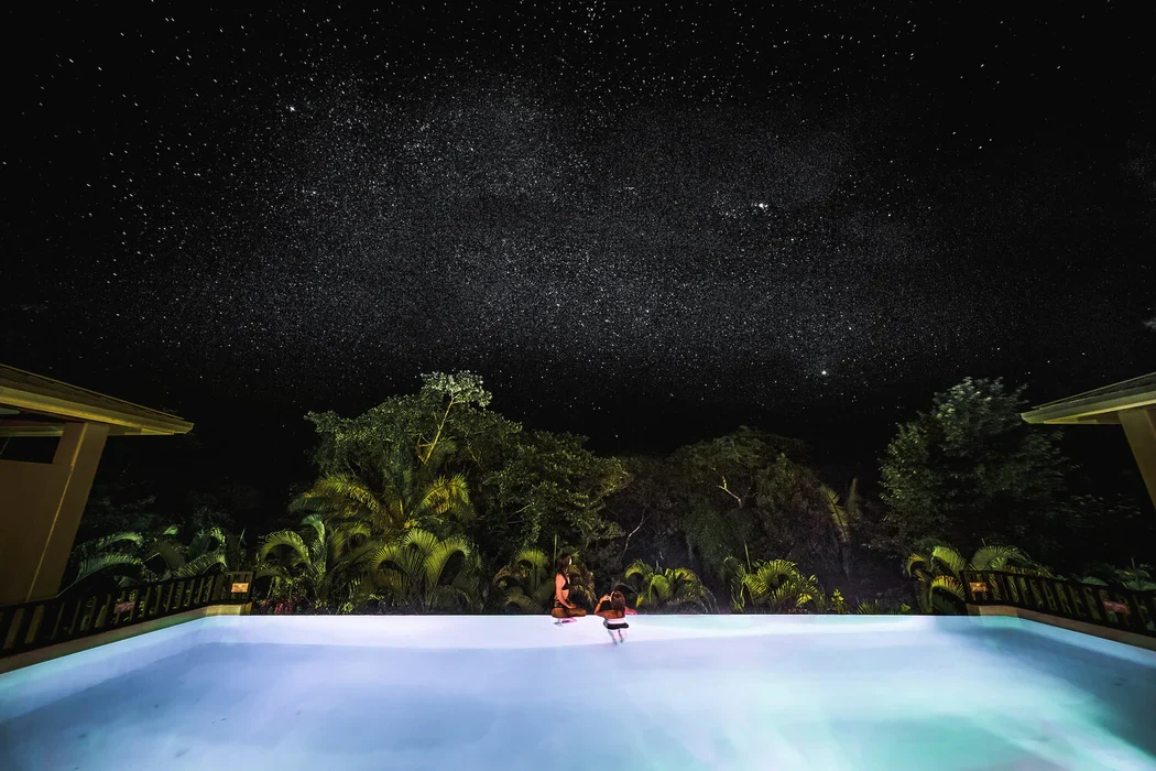 Couple beside the pool under a star-filled sky at Copal Tree Lodge, Belize