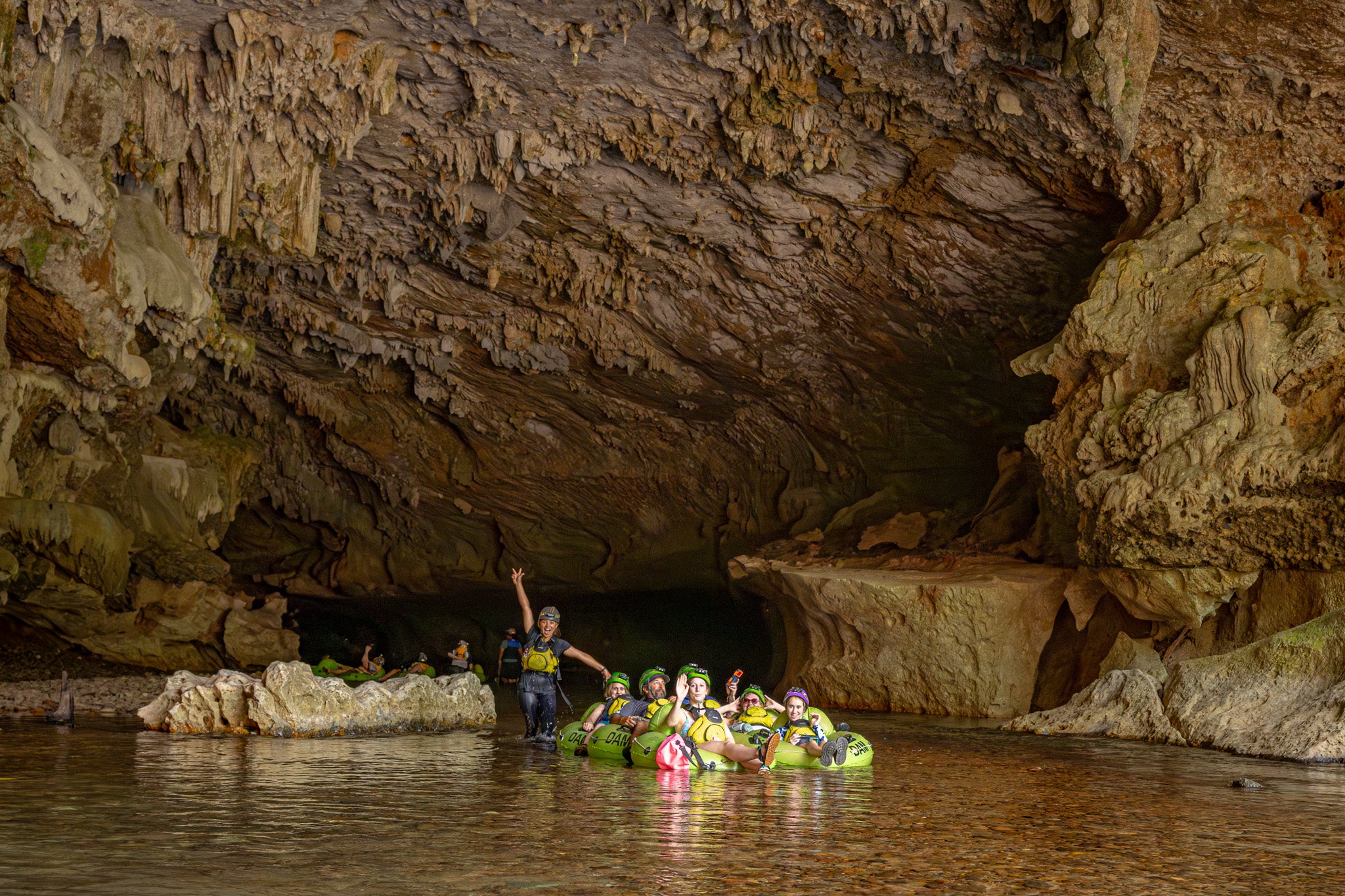 Travelers cave tubing together beneath limestone formations in Belize
