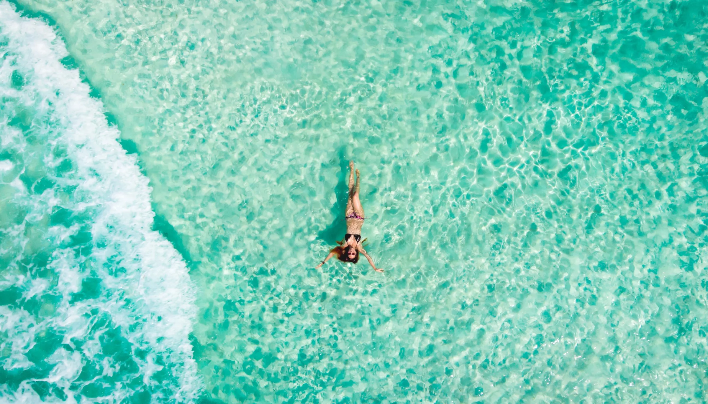 Overhead view of a swimmer floating in clear turquoise Caribbean water off Cozumel