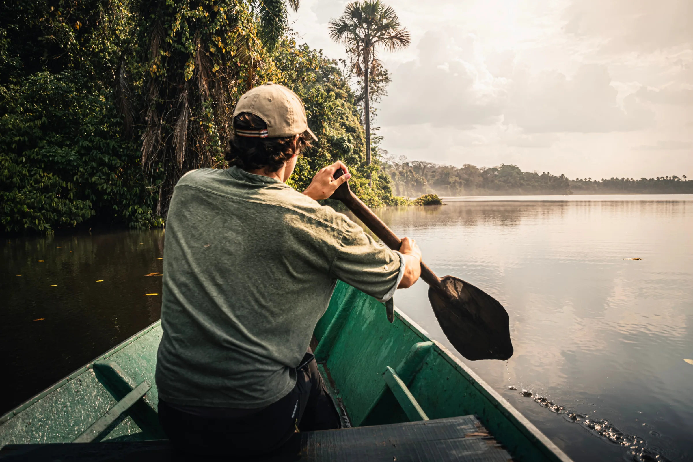 A traveler paddling a canoe on the Amazon River at sunset