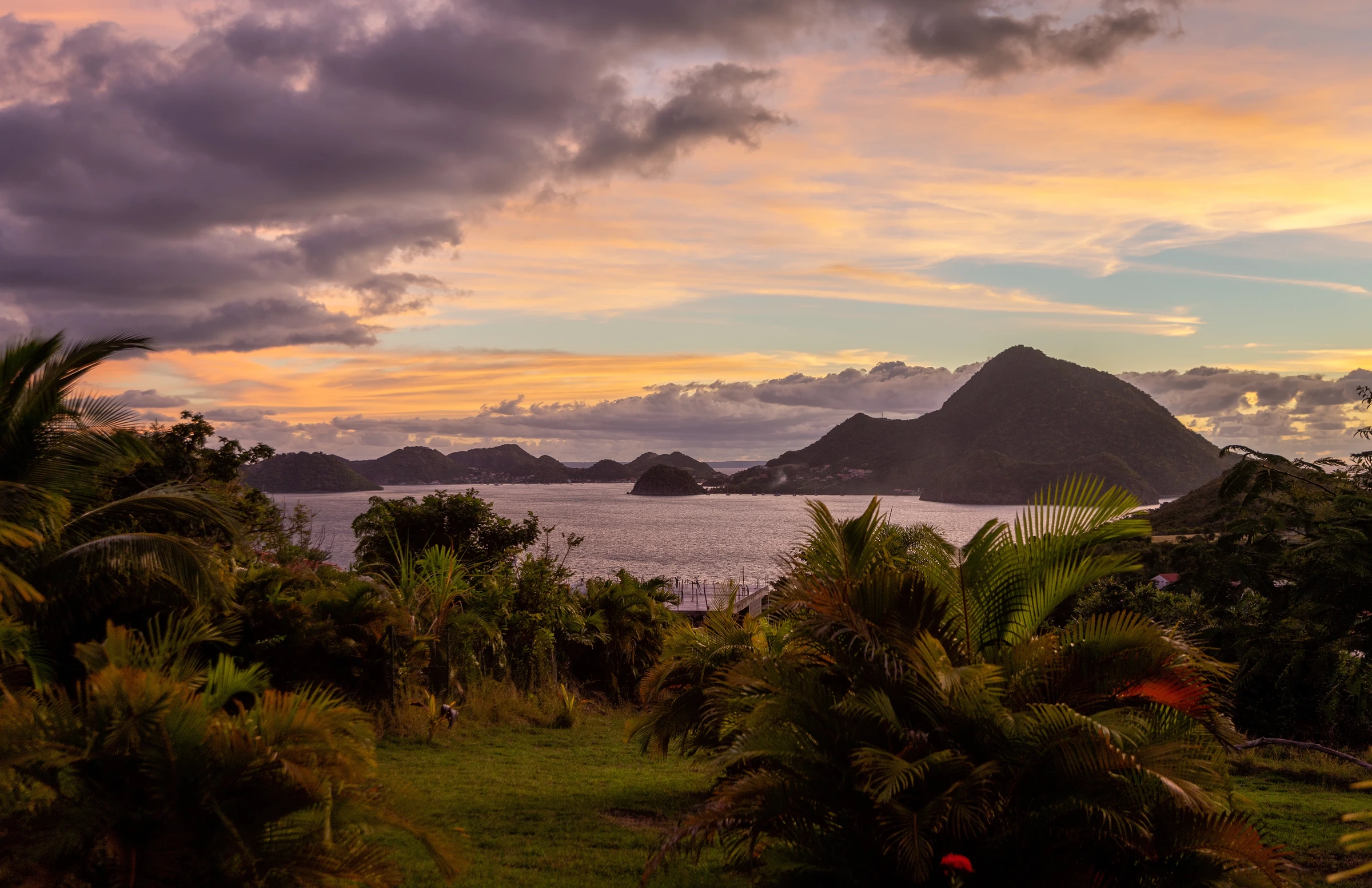 Sunset over palm trees and island mountains in Guadeloupe.