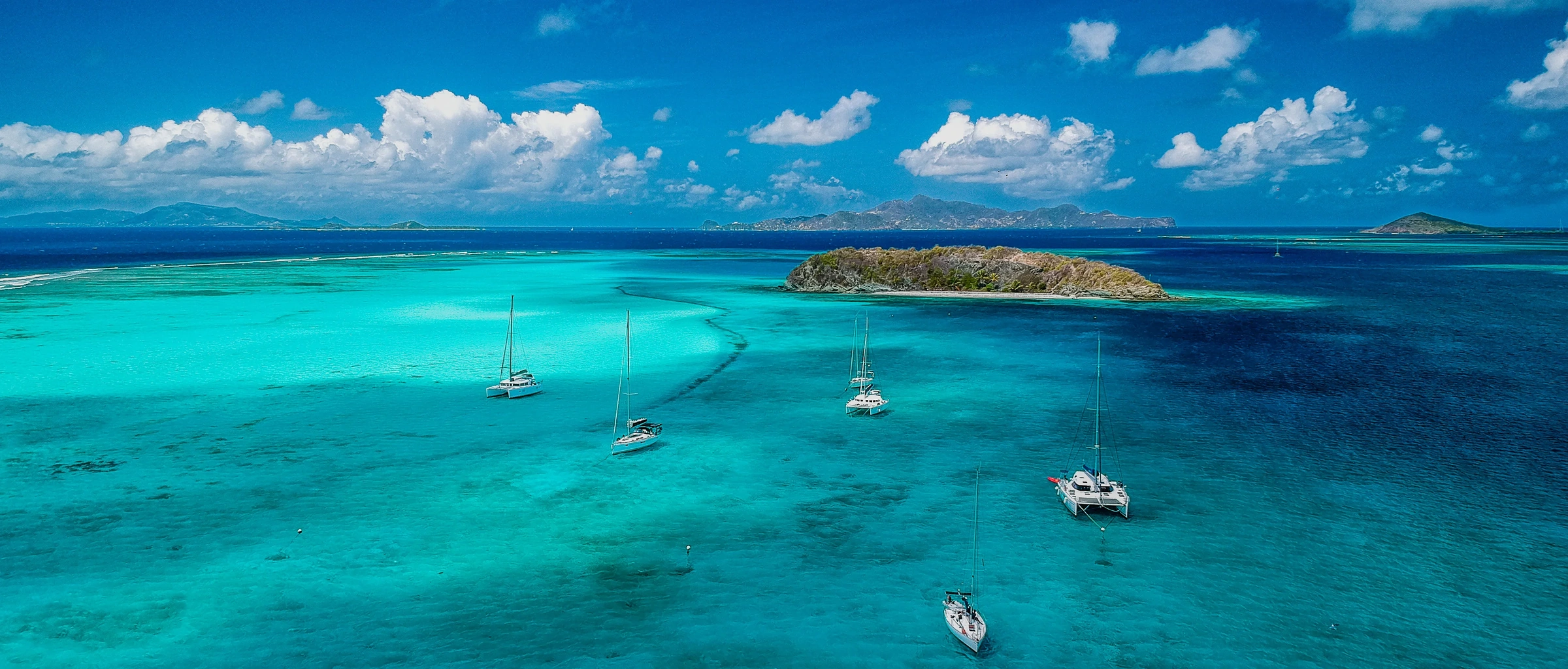 Sailboats in turquoise water among the Grenadine islands.