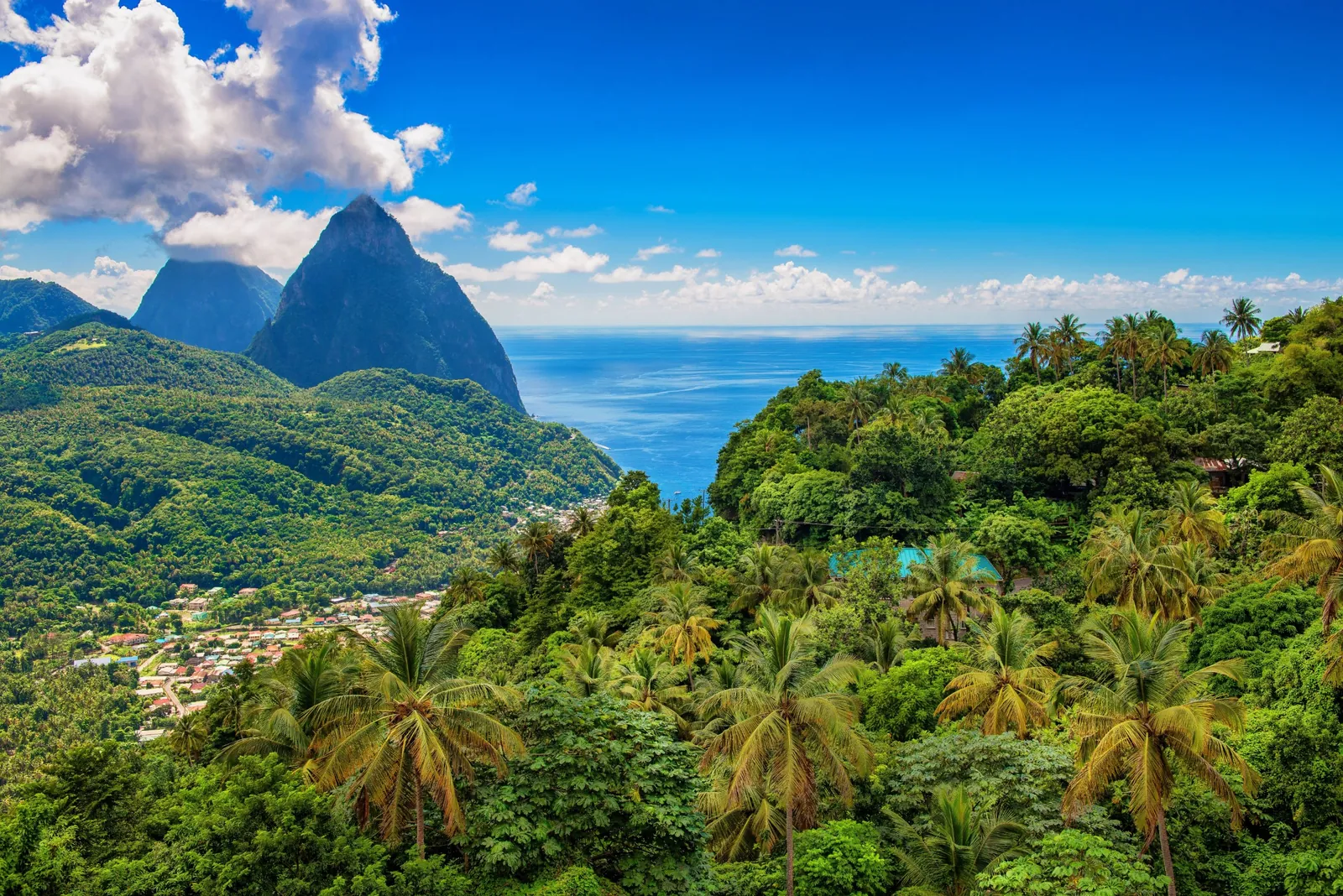 Palm-covered hills above the Soufrière valley, with the Pitons and the Caribbean Sea beyond.