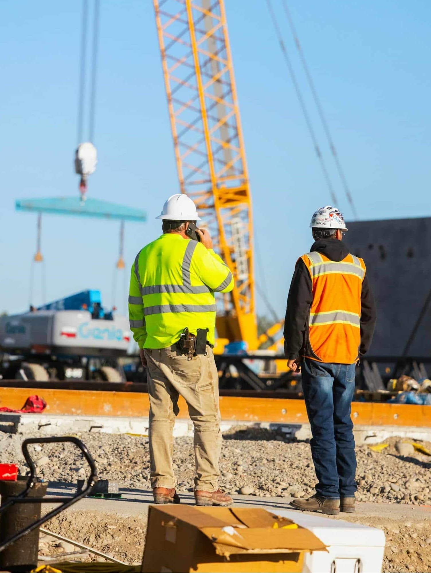 Construction workers building a tilt panel building with a crane in the background.