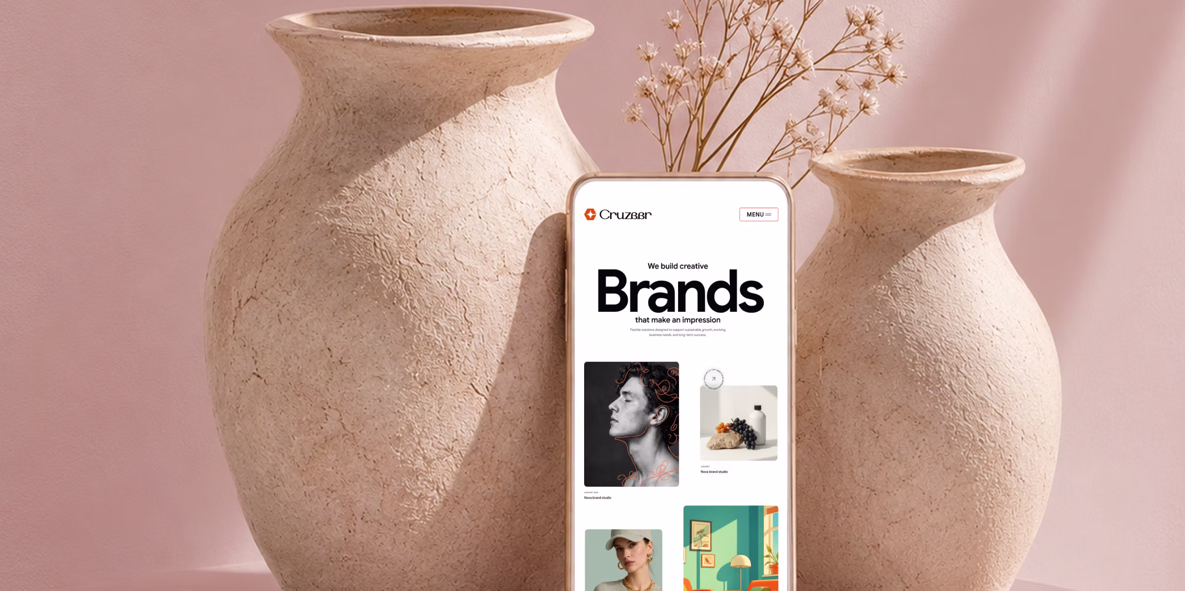 Smartphone displaying a website with the heading 'Brands' in bold, positioned between two large textured ceramic vases with dried flowers, against a soft pink background.