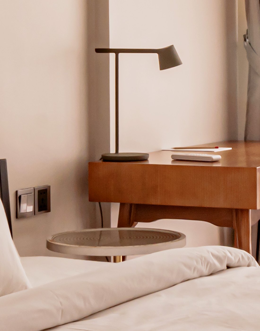 A furnished room at Commune Live, desk and bedside table