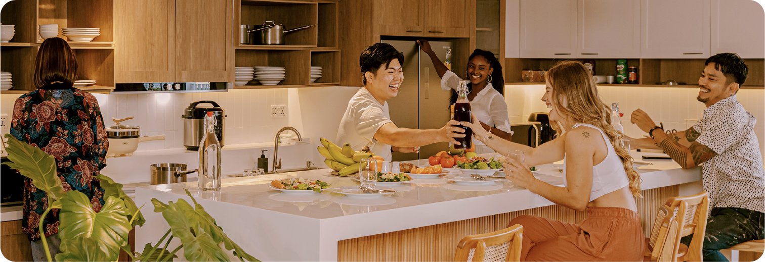 Housemates cooking and eating together in the shared kitchen
