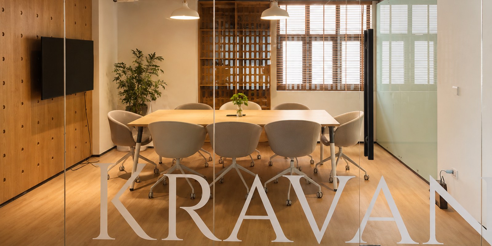 The Kravan meeting room through its glass wall, a table for six under two pendant lights