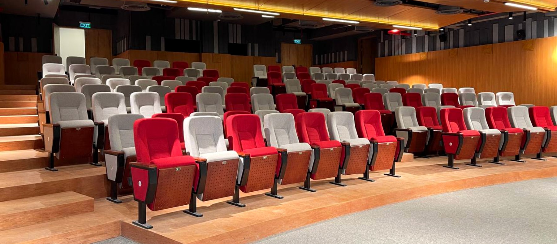 The Commune auditorium, tiered rows of red and grey seats under a timber ceiling