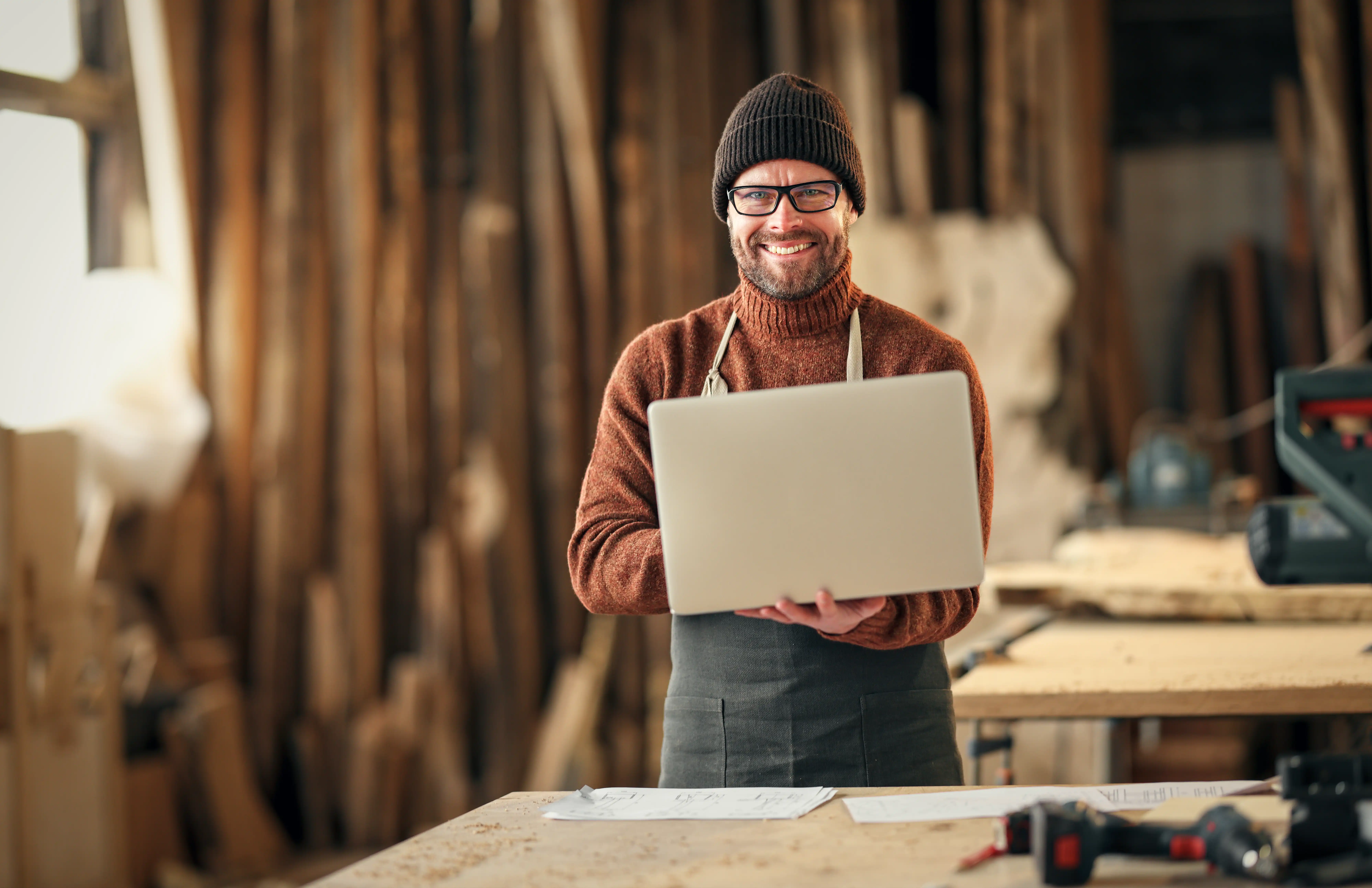 Handwerker mit Laptop in seiner Werkstatt