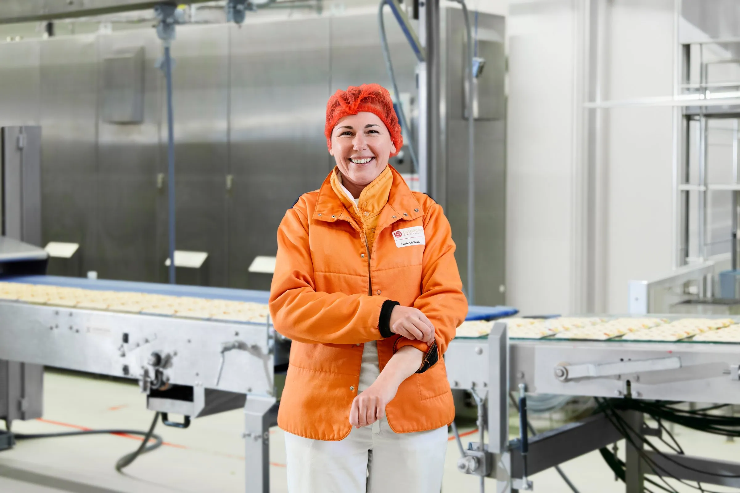 Keyvisual La Lorraine Tsjechië: medewerker in oranje jas in de productiehal