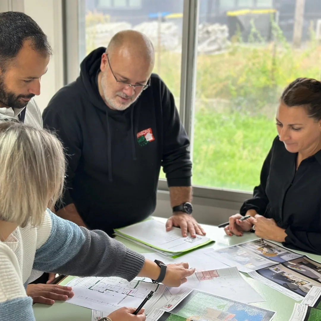 Portrait d'équipe en réunion autour des plans d'un projet