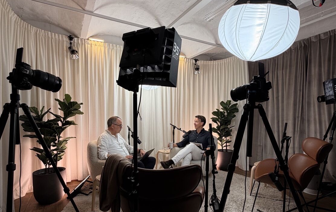 Studion sedd på avstånd, med kameror, lampor och två personer i samtal