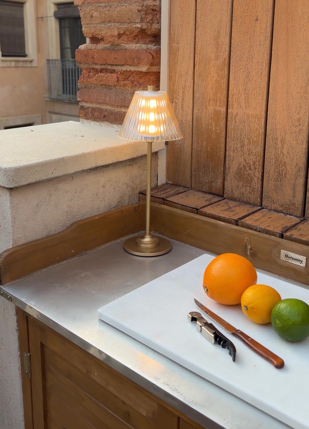 Corston rechargeable lamp with a fluted glass shade beside citrus and kitchen utensils.