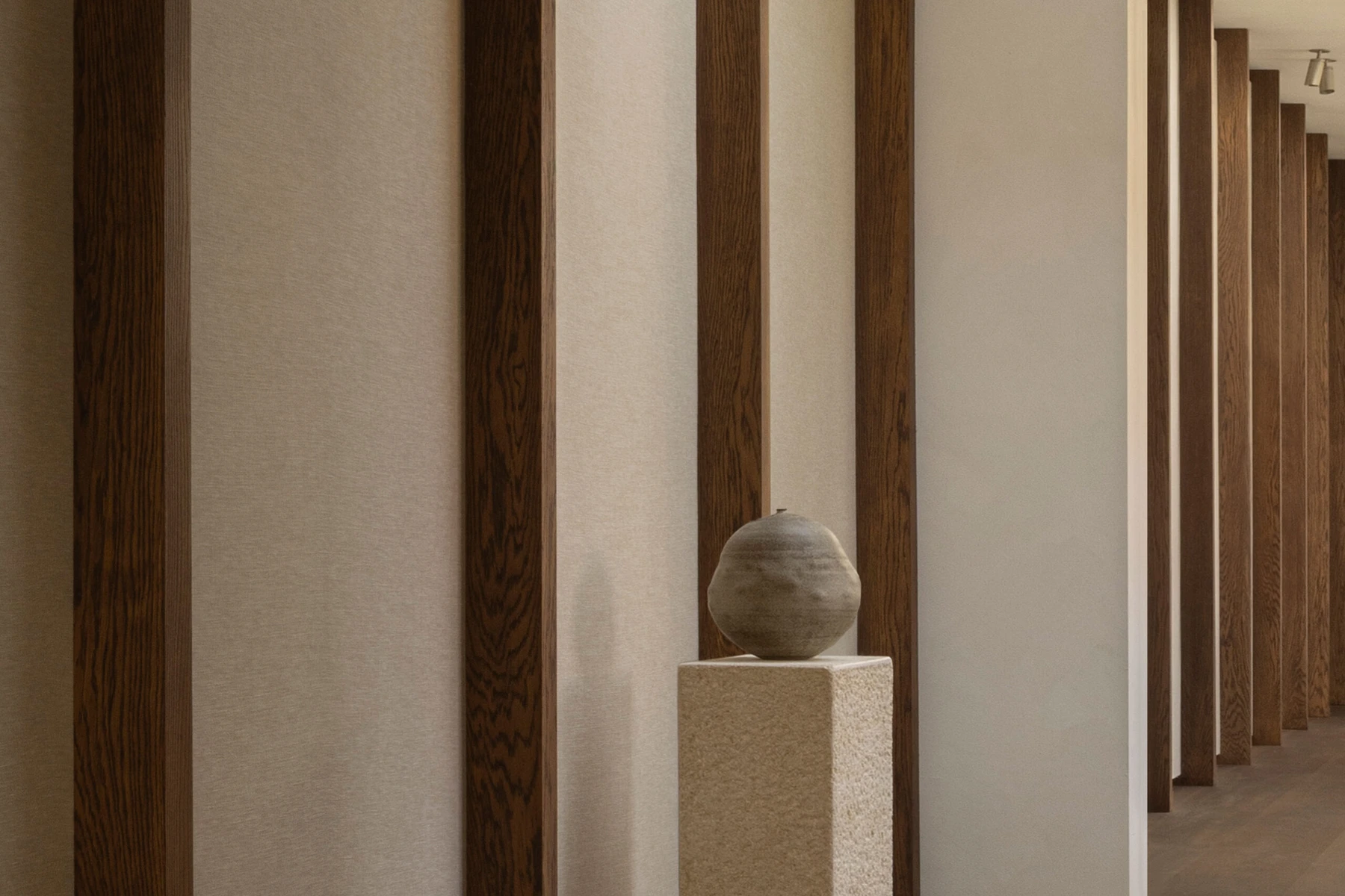 Dark timber uprights and textile panels at Norm Studio, with a ceramic vessel set on a stone plinth.