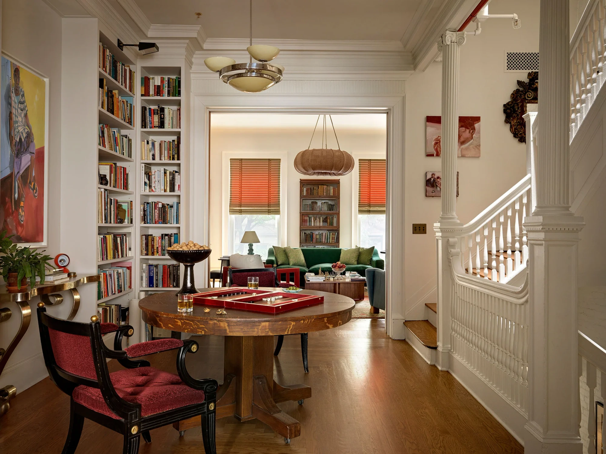 A layered library and sitting room in Beata Heuman’s Manhattan Brownstone, with red seating, green upholstery and sculptural lighting. Photo: Simon Brown.