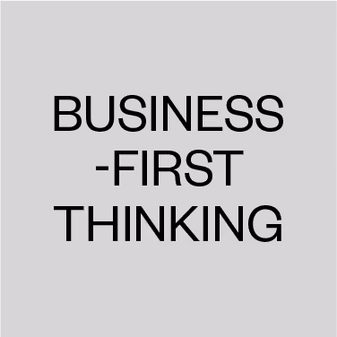Text on a gray background reading BUSINESS-FIRST THINKING in black capital letters.