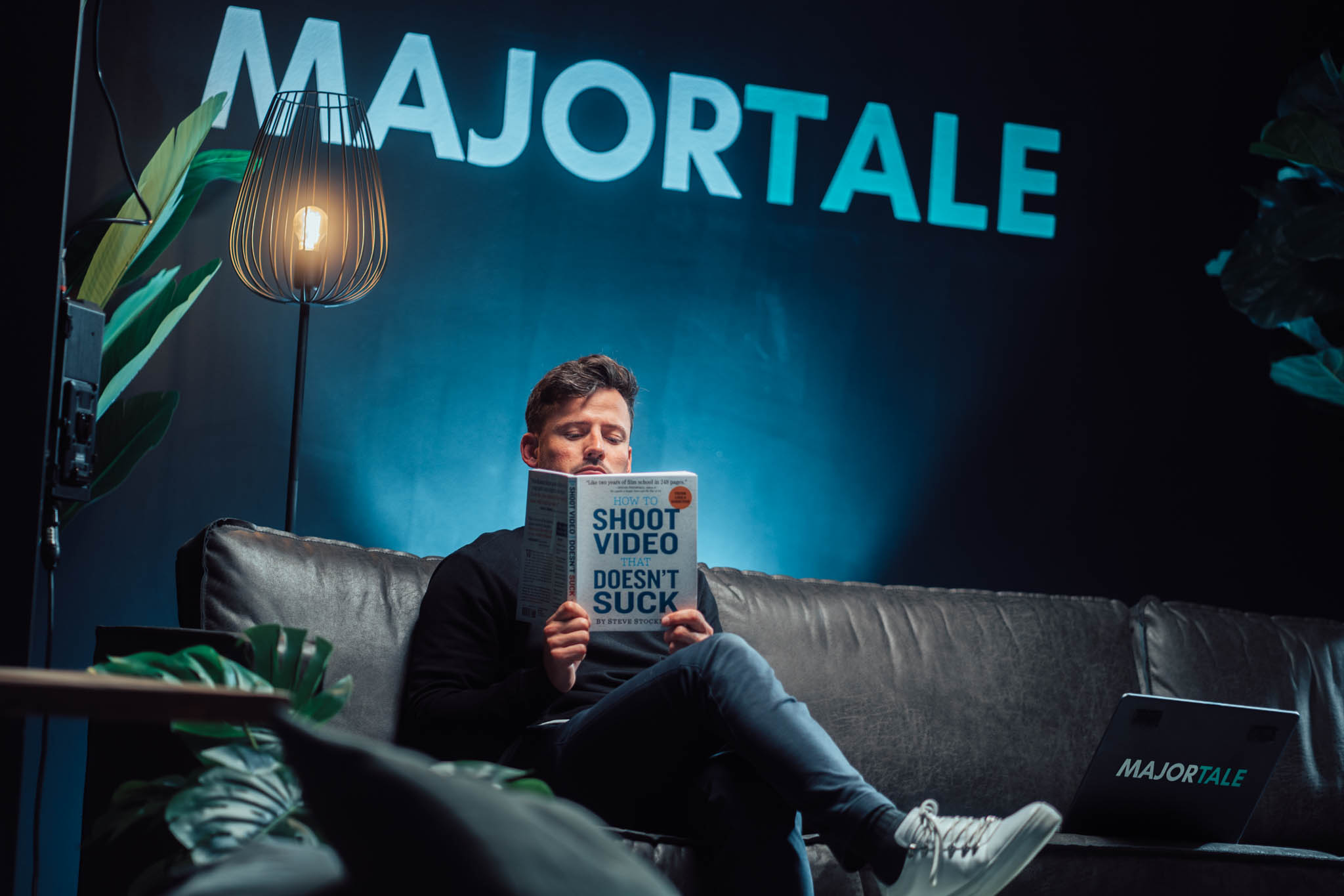 Man reading a book titled 'Shoot video that doesn't suck' in the Majortale studio