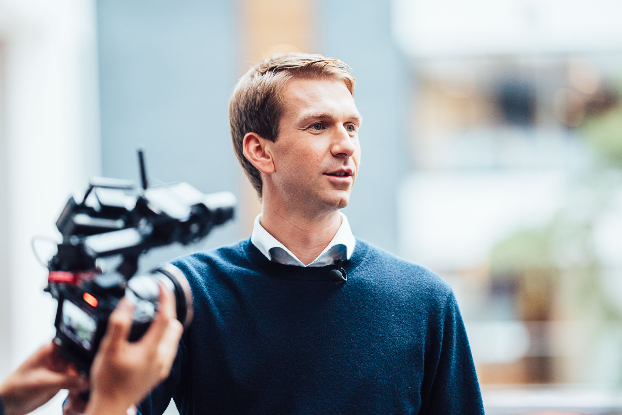 Man in a navy sweater being filmed for a corporate video