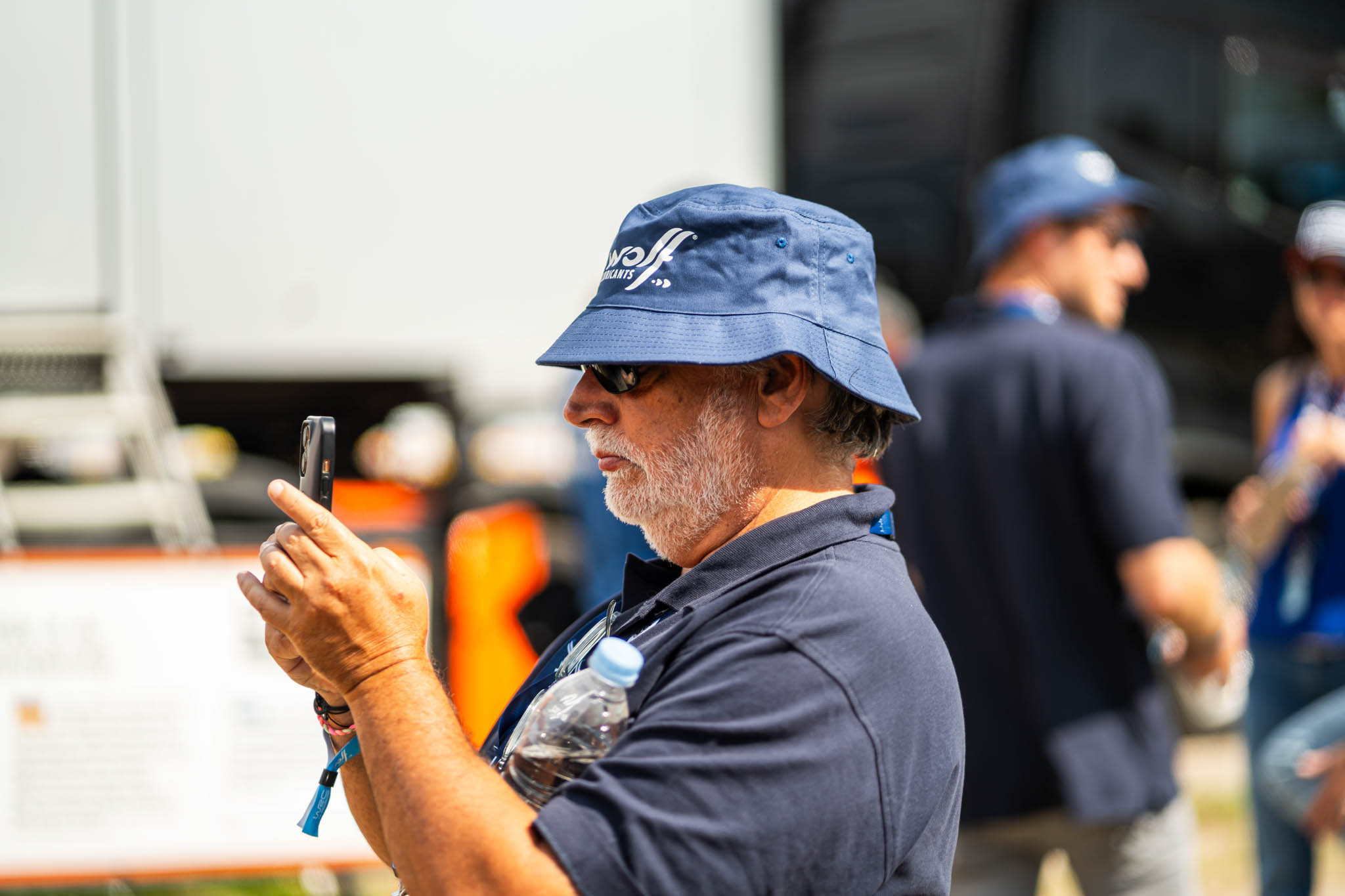 Man in a bucket hat filming with his phone at an event