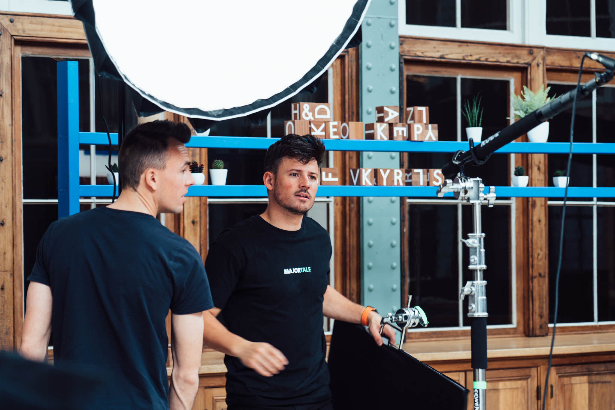 Two Majortale crew members talking on set between lights and props