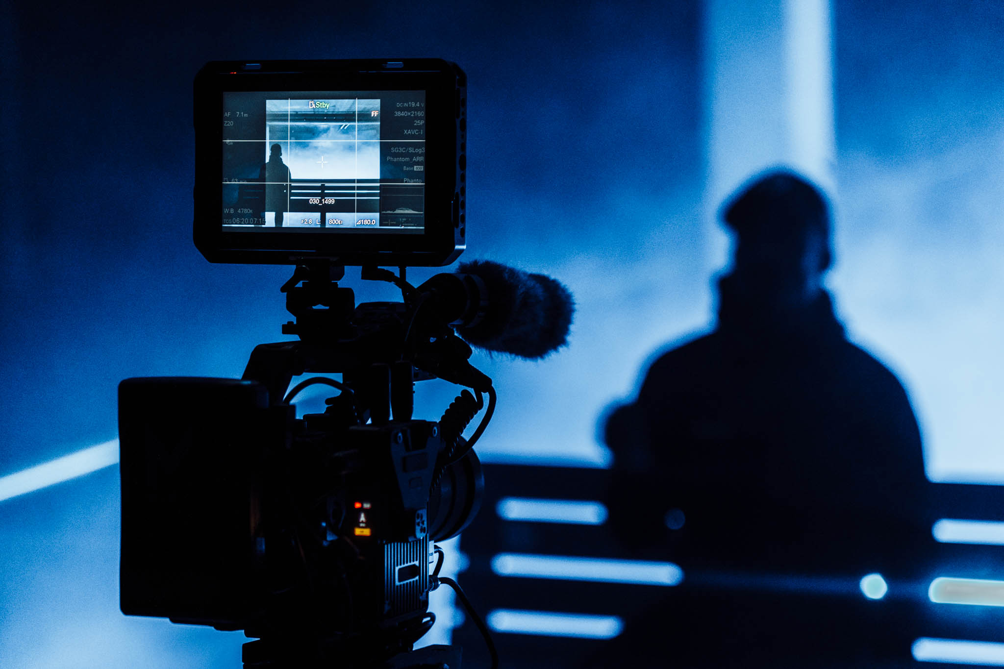 Cinema camera and monitor in front of a silhouette on a blue lit set