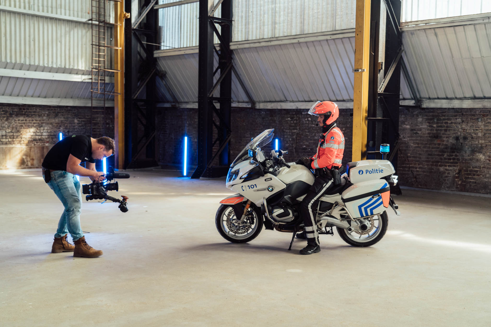 Crew member filming a police motorcyclist in a warehouse studio