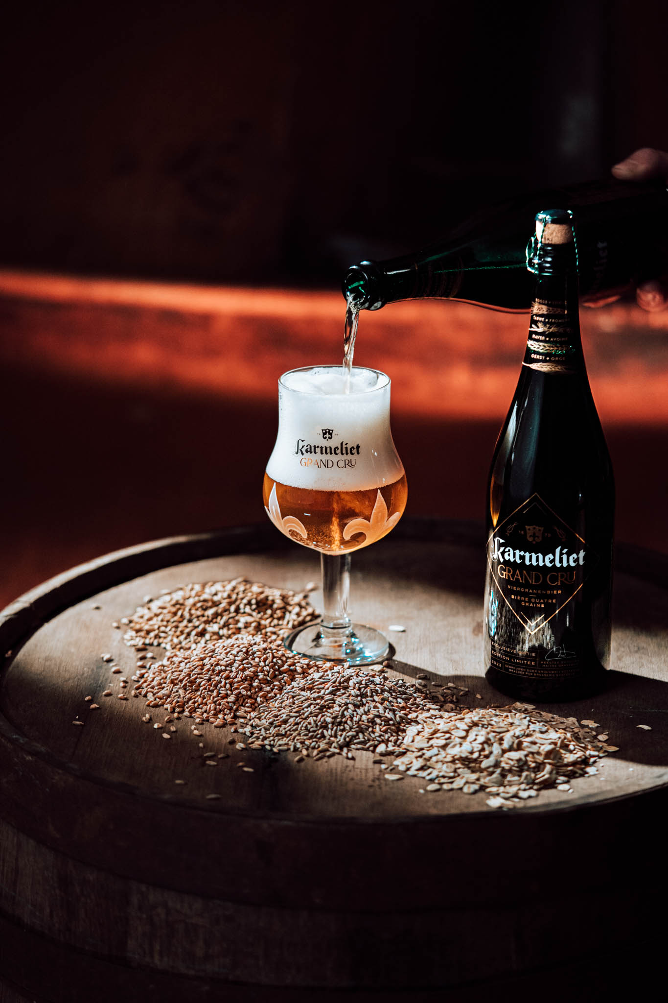 Karmeliet Grand Cru bottle and filled glass on a barrel with grain