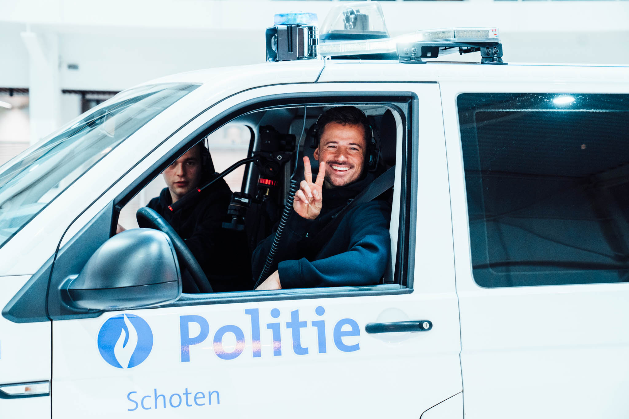 Smiling police officers in a Politie Schoten van during the recruitment shoot