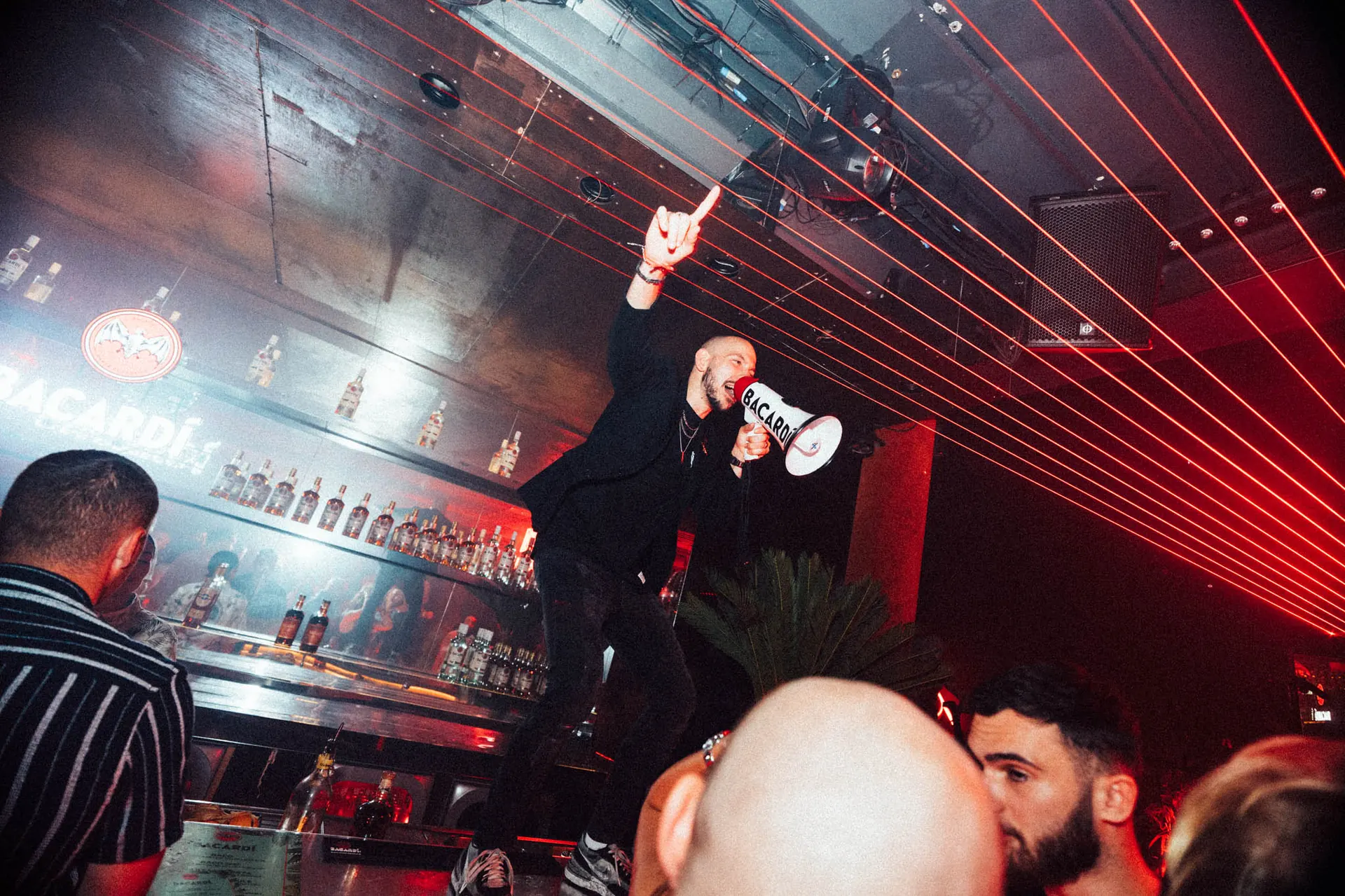 Host with a megaphone on the Bacardi bar under red laser lights