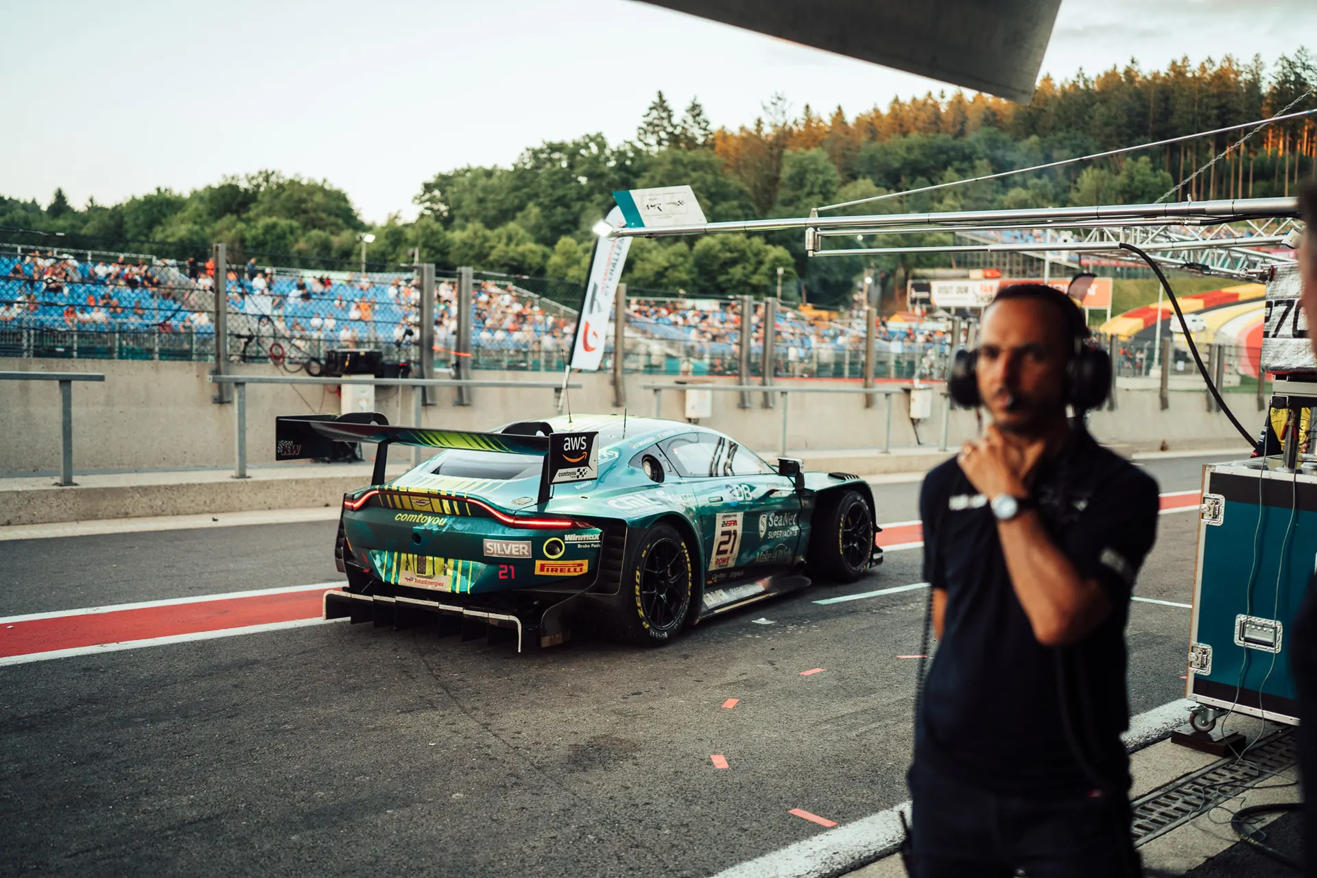 Crew member with headset in the pit lane next to a GT race car