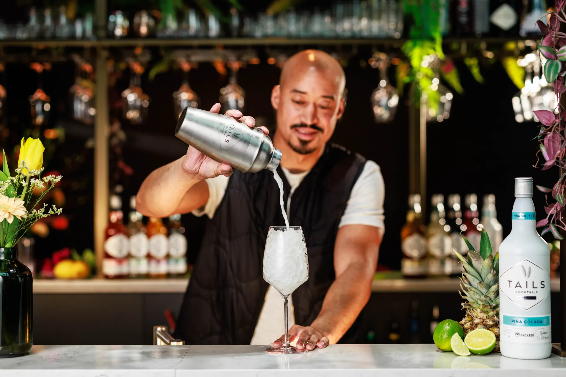 Bartender pouring a cocktail from a shaker at a Tails bar