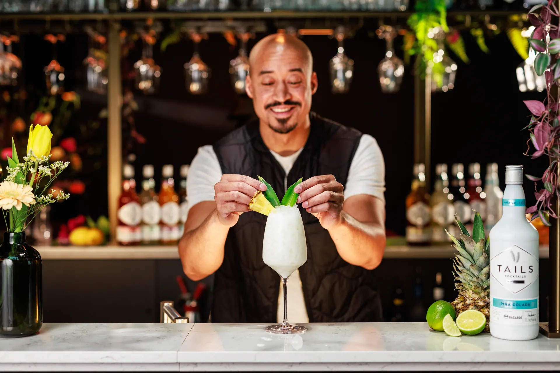 Bartender garnishing a white cocktail next to a Tails bottle