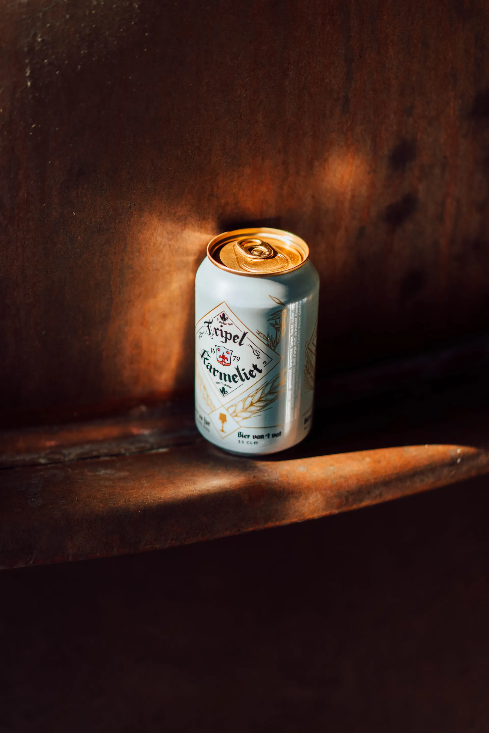 Tripel Karmeliet can in a beam of light on a wooden shelf