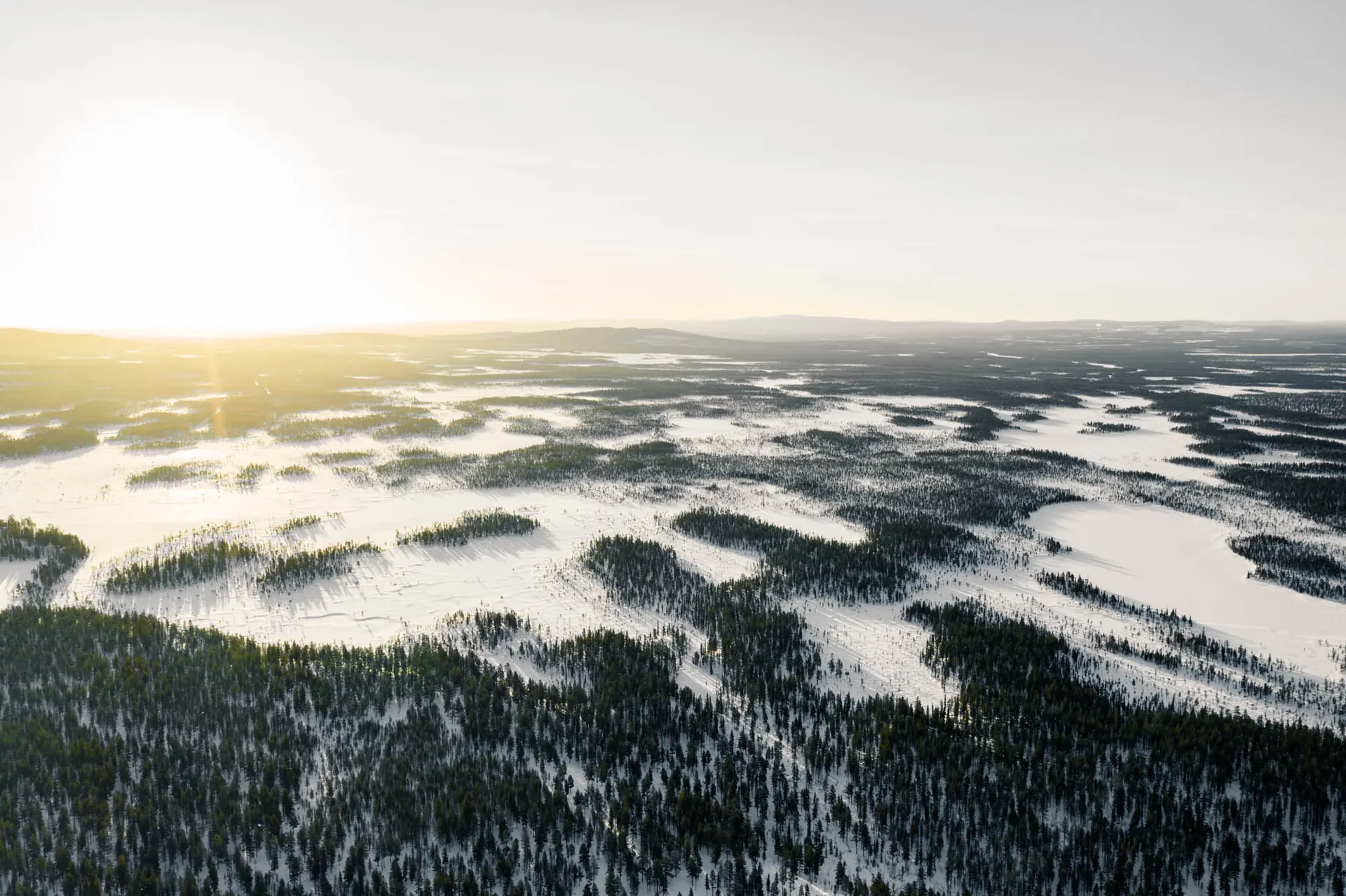 Aerial view of snowy forests and lakes in Swedish Lapland at sunrise