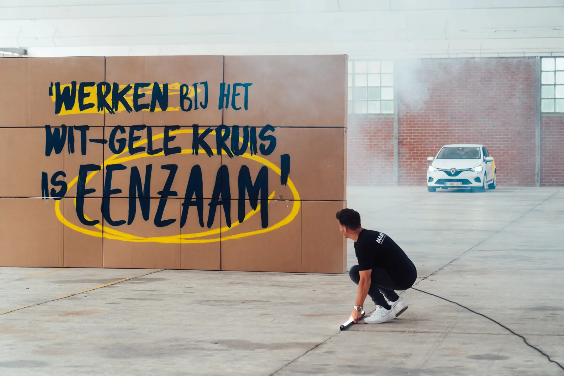 Cardboard wall reading 'Werken bij het Wit-Gele Kruis is eenzaam' on set