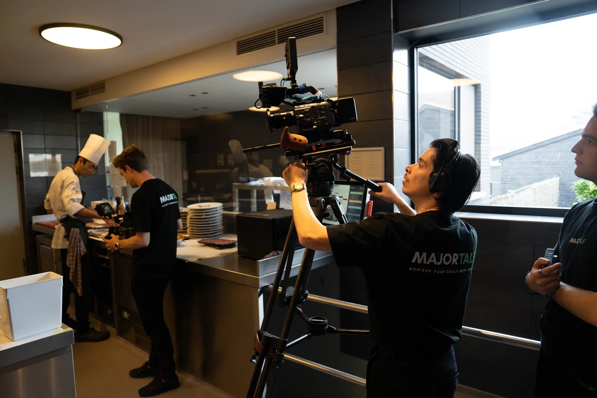Camera operator filming chefs in a restaurant kitchen