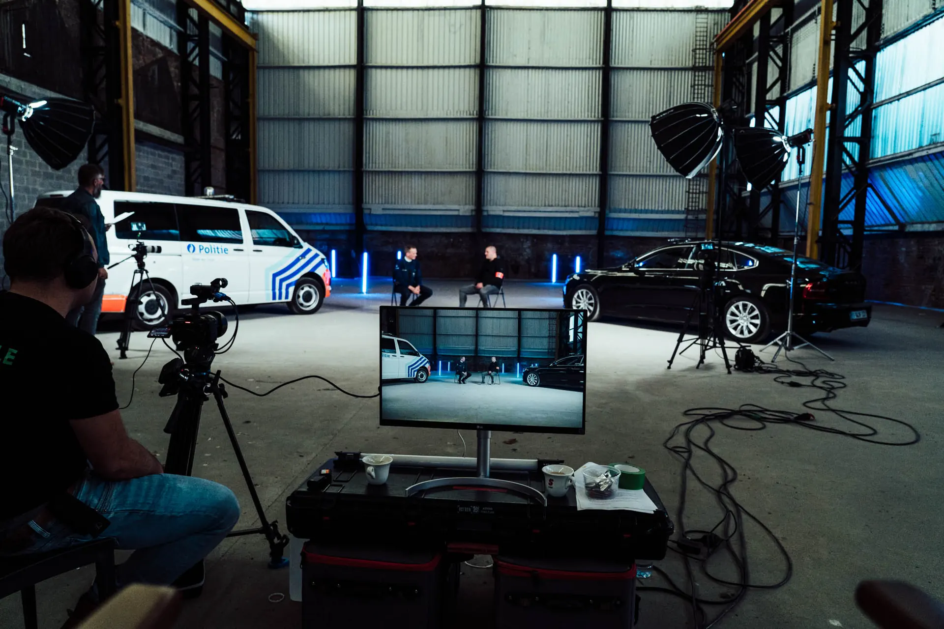 Video set in a warehouse with a police van, car and camera monitors