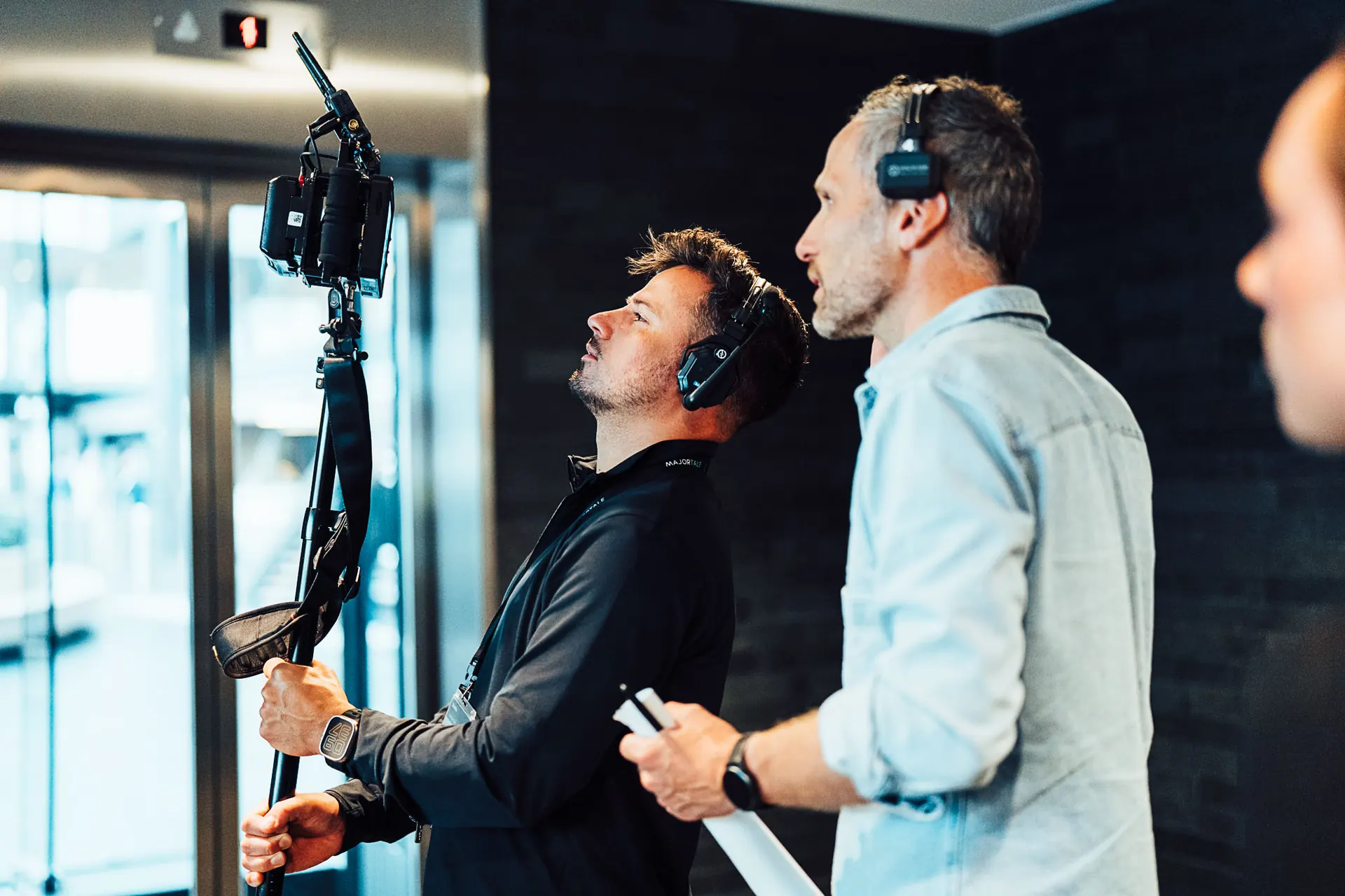 Crew member holding a boom mic next to a man during a corporate shoot