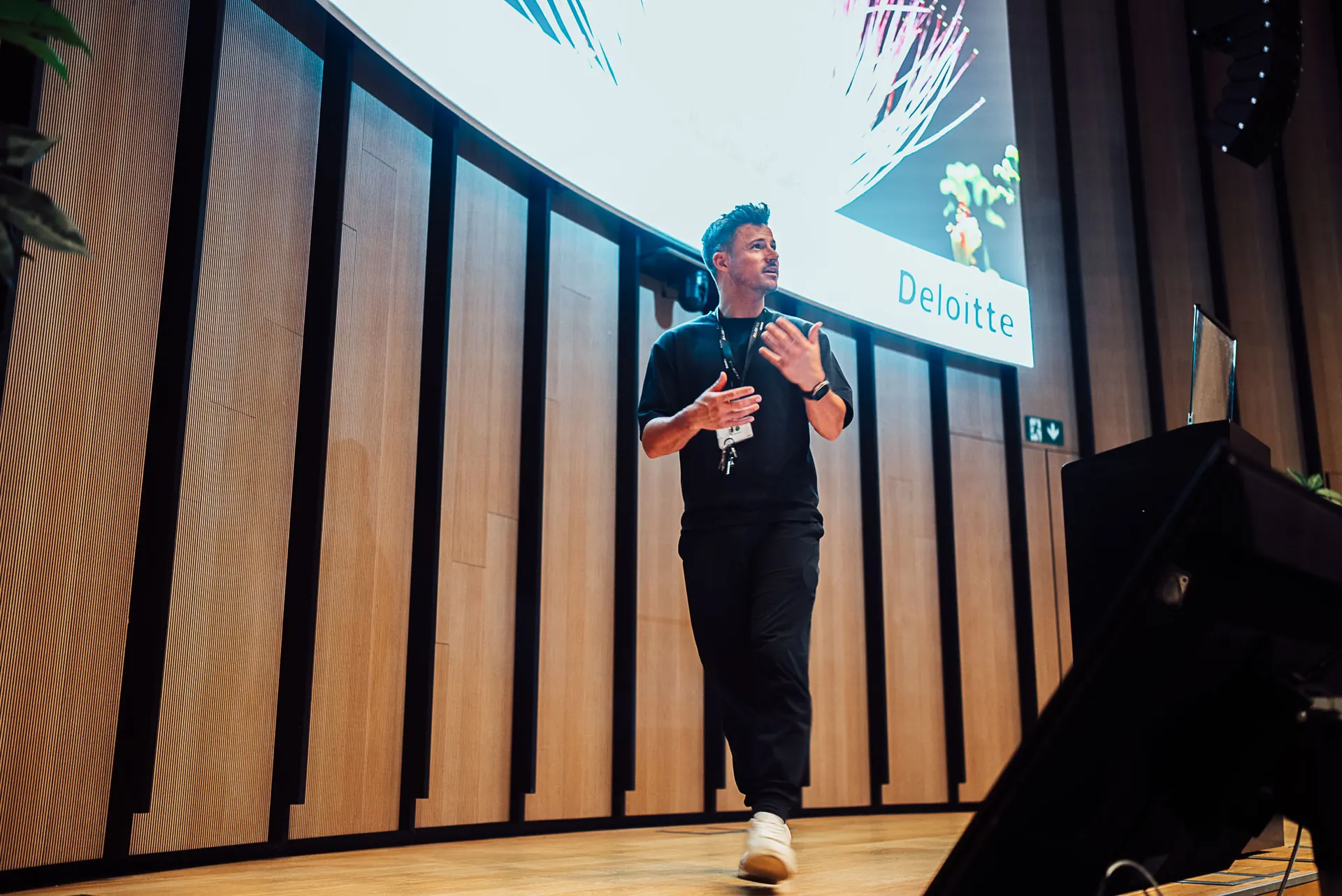 Speaker on stage in front of a Deloitte presentation