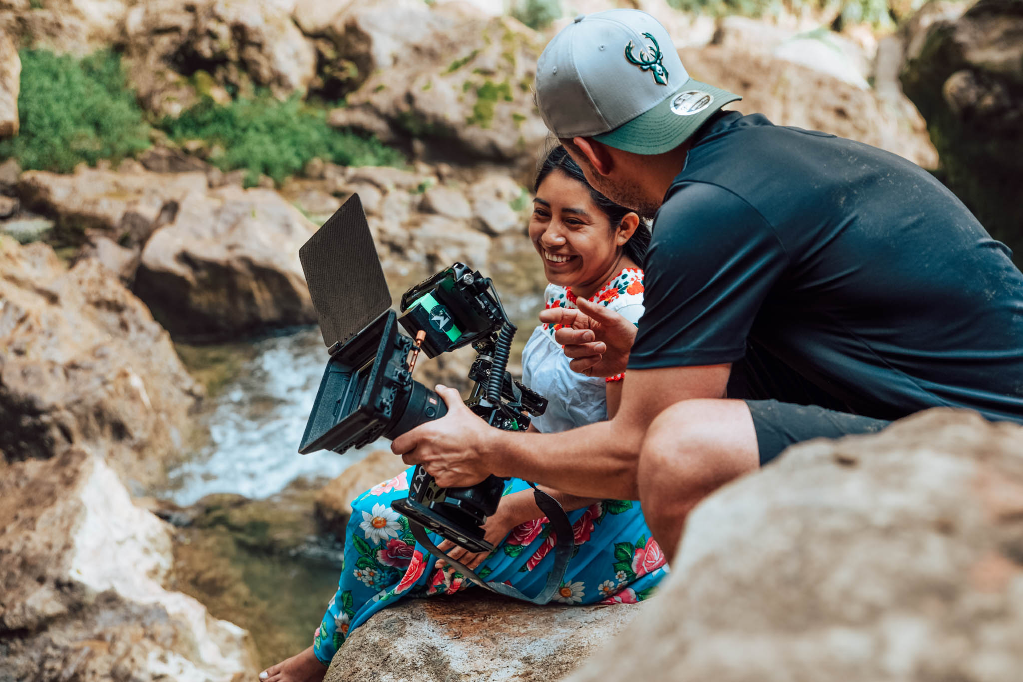 Majortale filmmaker showing footage on the camera to a coffee farmer by a river