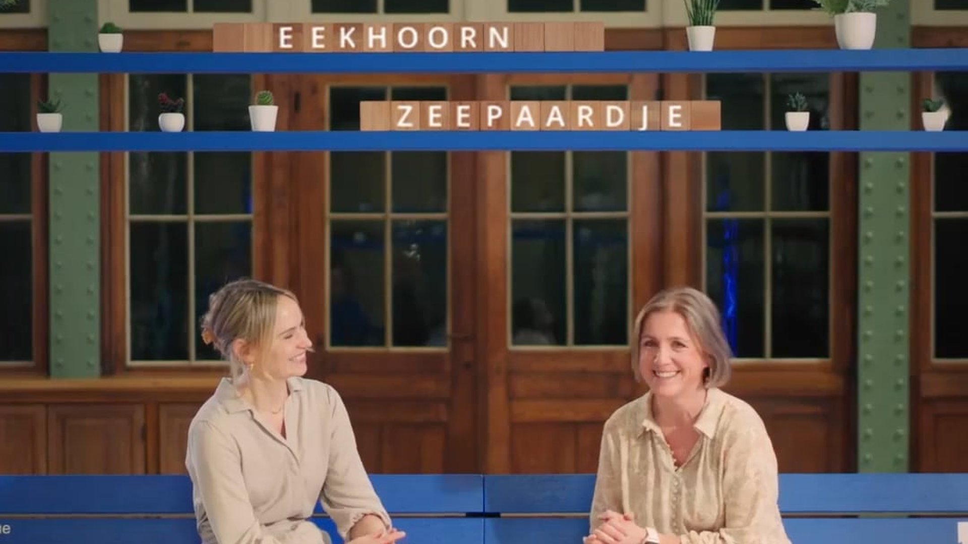 Two Bank van Breda project managers talking on a blue bench in front of wooden doors