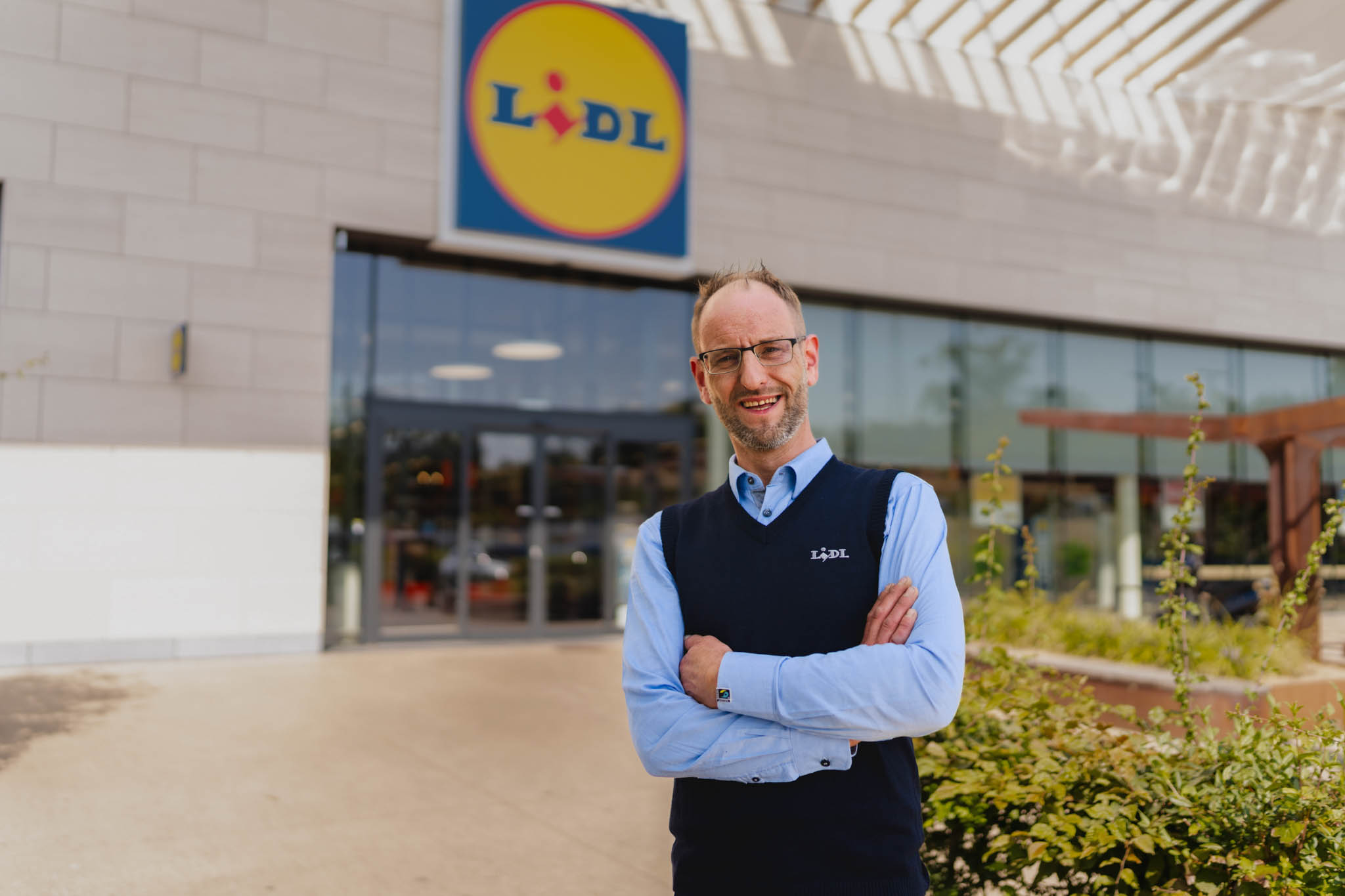 Lidl employee portrait in front of a Lidl store, from the honest job ad campaign